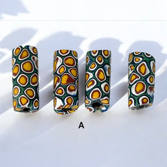 A set of vintage Venetian millefiori African trade beads in vibrant green and yellow. The tube-shaped glass beads, originating from Ghana, feature intricate floral patterns and showcase the rich history of 19th and 20th-century trade. Some beads show minor chips due to age, adding to their authentic vintage charm.