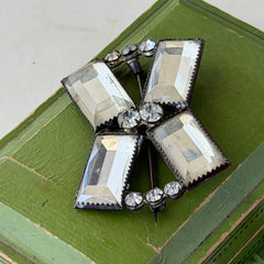 Vintage Victorian silver‑tone bow brooch with emerald‑cut clear glass stones and paste rhinestones, shown from multiple angles highlighting its antique patina and craftsmanship.