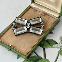 Vintage Victorian silver‑tone bow brooch with emerald‑cut clear glass stones and paste rhinestones, shown from multiple angles highlighting its antique patina and craftsmanship.