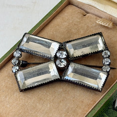 Vintage Victorian silver‑tone bow brooch with emerald‑cut clear glass stones and paste rhinestones, shown from multiple angles highlighting its antique patina and craftsmanship.