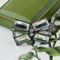 Vintage Victorian silver‑tone bow brooch with emerald‑cut clear glass stones and paste rhinestones, shown from multiple angles highlighting its antique patina and craftsmanship.
