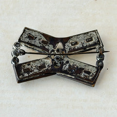 Vintage Victorian silver‑tone bow brooch with emerald‑cut clear glass stones and paste rhinestones, shown from multiple angles highlighting its antique patina and craftsmanship.
