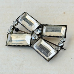 Vintage Victorian silver‑tone bow brooch with emerald‑cut clear glass stones and paste rhinestones, shown from multiple angles highlighting its antique patina and craftsmanship.