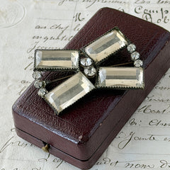 Vintage Victorian silver‑tone bow brooch with emerald‑cut clear glass stones and paste rhinestones, shown from multiple angles highlighting its antique patina and craftsmanship.