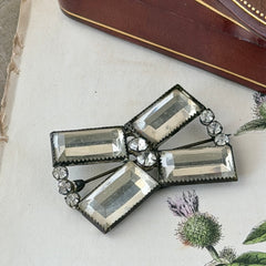 Vintage Victorian silver‑tone bow brooch with emerald‑cut clear glass stones and paste rhinestones, shown from multiple angles highlighting its antique patina and craftsmanship.