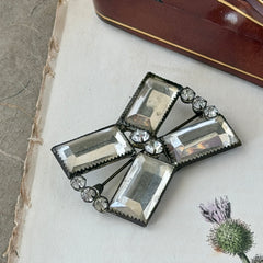 Vintage Victorian silver‑tone bow brooch with emerald‑cut clear glass stones and paste rhinestones, shown from multiple angles highlighting its antique patina and craftsmanship.