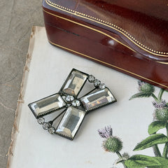 Vintage Victorian silver‑tone bow brooch with emerald‑cut clear glass stones and paste rhinestones, shown from multiple angles highlighting its antique patina and craftsmanship.
