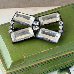 Vintage Victorian silver‑tone bow brooch with emerald‑cut clear glass stones and paste rhinestones, shown from multiple angles highlighting its antique patina and craftsmanship.