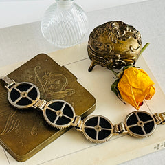 Vintage Victorian Revival gold‑tone bracelet with round black disks, filigree floral overlays, and clear rhinestone centers shown in various angles and styling arrangements.