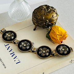 Vintage Victorian Revival gold‑tone bracelet with round black disks, filigree floral overlays, and clear rhinestone centers shown in various angles and styling arrangements.