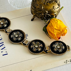 Vintage Victorian Revival gold‑tone bracelet with round black disks, filigree floral overlays, and clear rhinestone centers shown in various angles and styling arrangements.