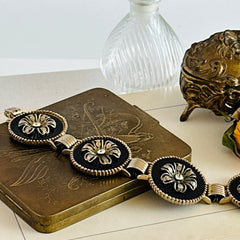 Vintage Victorian Revival gold‑tone bracelet with round black disks, filigree floral overlays, and clear rhinestone centers shown in various angles and styling arrangements.