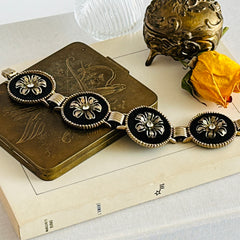 Vintage Victorian Revival gold‑tone bracelet with round black disks, filigree floral overlays, and clear rhinestone centers shown in various angles and styling arrangements.