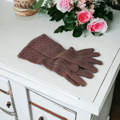 Vintage medium-length brown cotton gloves with a raised knit pattern on the arm and back of the hand, gently worn and in very good condition, laid flat to show texture and detail.