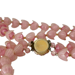 Vintage 1950s West Germany double-strand necklace displayed on black velvet stand, featuring frosted pink plastic petal beads encasing darker pink faceted centers, finished with a round pink cabochon clasp.