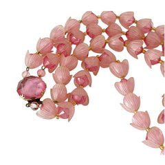 Vintage 1950s West Germany double-strand necklace displayed on black velvet stand, featuring frosted pink plastic petal beads encasing darker pink faceted centers, finished with a round pink cabochon clasp.