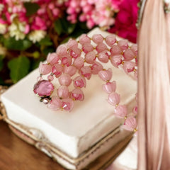 Vintage 1950s West Germany double-strand necklace displayed on black velvet stand, featuring frosted pink plastic petal beads encasing darker pink faceted centers, finished with a round pink cabochon clasp.