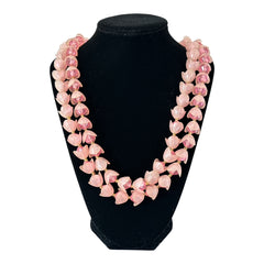 Vintage 1950s West Germany double-strand necklace displayed on black velvet stand, featuring frosted pink plastic petal beads encasing darker pink faceted centers, finished with a round pink cabochon clasp.