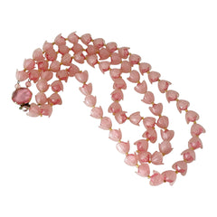 Vintage 1950s West Germany double-strand necklace displayed on black velvet stand, featuring frosted pink plastic petal beads encasing darker pink faceted centers, finished with a round pink cabochon clasp.