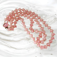 Vintage 1950s West Germany double-strand necklace displayed on black velvet stand, featuring frosted pink plastic petal beads encasing darker pink faceted centers, finished with a round pink cabochon clasp.