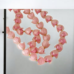 Vintage 1950s West Germany double-strand necklace displayed on black velvet stand, featuring frosted pink plastic petal beads encasing darker pink faceted centers, finished with a round pink cabochon clasp.