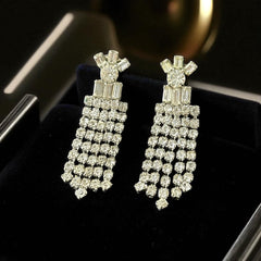Vintage 1960s clip-on earrings with cascading clear rhinestone dangles, featuring chaton and baguette stones in a waterfall design, displayed on a black jewelry box.