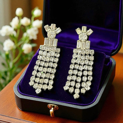 Vintage 1960s clip-on earrings with cascading clear rhinestone dangles, featuring chaton and baguette stones in a waterfall design