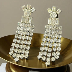 Vintage 1960s clip-on earrings with cascading clear rhinestone dangles, featuring chaton and baguette stones in a waterfall design