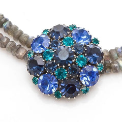  A stunning vintage Weiss crystal dome brooch in shades of blue and teal, paired with a double strand of shiny blue and gray faceted labradorite rondelles. The brooch can be worn centered, off-center, or separately, offering versatile styling. Finished with sterling silver spacers and a toggle clasp, this unique piece blends vintage charm with modern craftsmanship, signed Weiss on the back and featuring the EM tag in Etruscan alphabet for Elisabeth Michel-Meyrueix.
