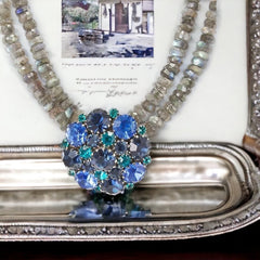  A stunning vintage Weiss crystal dome brooch in shades of blue and teal, paired with a double strand of shiny blue and gray faceted labradorite rondelles. The brooch can be worn centered, off-center, or separately, offering versatile styling. Finished with sterling silver spacers and a toggle clasp, this unique piece blends vintage charm with modern craftsmanship, signed Weiss on the back and featuring the EM tag in Etruscan alphabet for Elisabeth Michel-Meyrueix.

