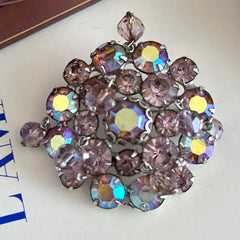 Vintage 1950s Weiss round brooch with light amethyst and amethyst AB rhinestones arranged in a layered cluster, set in rhodium‑plated metal with a dangling bead accent