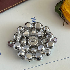 Vintage 1950s Weiss round brooch with light amethyst and amethyst AB rhinestones arranged in a layered cluster, set in rhodium‑plated metal with a dangling bead accent