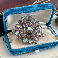 Vintage 1950s Weiss round brooch with light amethyst and amethyst AB rhinestones arranged in a layered cluster, set in rhodium‑plated metal with a dangling bead accent