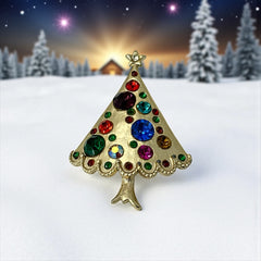 Vintage gold-tone Christmas tree brooch with multicolor rhinestones and scalloped edges, featuring a star at the top and textured detailing; back view shows pin clasp and trunk-shaped base, typical of 1980s–1990s holiday jewelry.