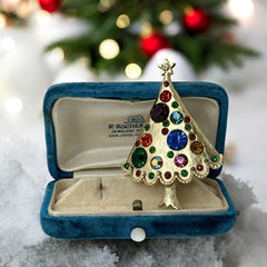 Vintage gold-tone Christmas tree brooch with multicolor rhinestones and scalloped edges, featuring a star at the top and textured detailing; back view shows pin clasp and trunk-shaped base, typical of 1980s–1990s holiday jewelry.