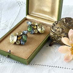 Vintage 1950s gold tone clip‑on earrings with yellow, blue, and green rhinestones in oval, pear, marquise, and emerald cuts, shown from multiple angles.