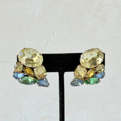 Vintage 1950s gold tone clip‑on earrings with yellow, blue, and green rhinestones in oval, pear, marquise, and emerald cuts, shown from multiple angles.
