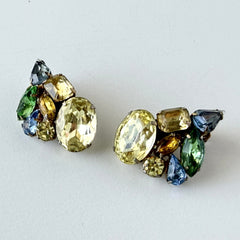 Vintage 1950s gold tone clip‑on earrings with yellow, blue, and green rhinestones in oval, pear, marquise, and emerald cuts, shown from multiple angles.