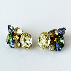 Vintage 1950s gold tone clip‑on earrings with yellow, blue, and green rhinestones in oval, pear, marquise, and emerald cuts, shown from multiple angles.