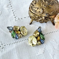 Vintage 1950s gold tone clip‑on earrings with yellow, blue, and green rhinestones in oval, pear, marquise, and emerald cuts, shown from multiple angles.