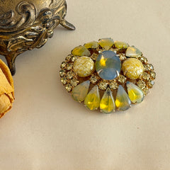 Vintage gold‑tone brooch with blue‑gray givre cabochon, yellow givre teardrops, confetti Lucite cabochons, and yellow chaton rhinestones.
