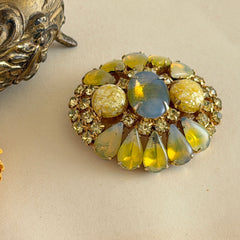 Vintage gold‑tone brooch with blue‑gray givre cabochon, yellow givre teardrops, confetti Lucite cabochons, and yellow chaton rhinestones.