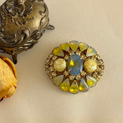 Vintage gold‑tone brooch with blue‑gray givre cabochon, yellow givre teardrops, confetti Lucite cabochons, and yellow chaton rhinestones.