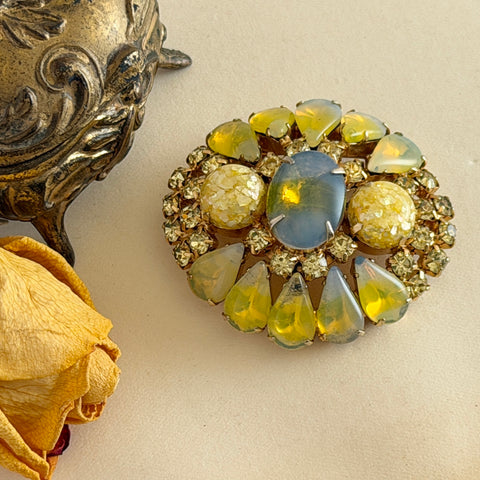 Vintage gold‑tone brooch with blue‑gray givre cabochon, yellow givre teardrops, confetti Lucite cabochons, and yellow chaton rhinestones.
