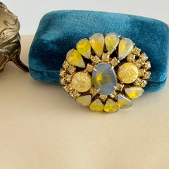 Vintage gold‑tone brooch with blue‑gray givre cabochon, yellow givre teardrops, confetti Lucite cabochons, and yellow chaton rhinestones.