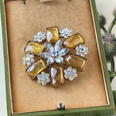 Vintage gold‑tone floral brooch with yellow emerald‑cut rhinestones and clear AB rhinestone clusters.