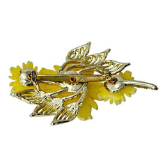Vintage yellow celluloid floral brooch from the 1950s featuring three gradient yellow-to-white flowers with clear rhinestone centers, accented by light gold-tone openwork leaves.