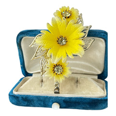 Vintage yellow celluloid floral brooch from the 1950s featuring three gradient yellow-to-white flowers with clear rhinestone centers, accented by light gold-tone openwork leaves.