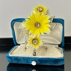Vintage yellow celluloid floral brooch from the 1950s featuring three gradient yellow-to-white flowers with clear rhinestone centers, accented by light gold-tone openwork leaves.