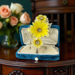 Vintage yellow celluloid floral brooch from the 1950s featuring three gradient yellow-to-white flowers with clear rhinestone centers, accented by light gold-tone openwork leaves.